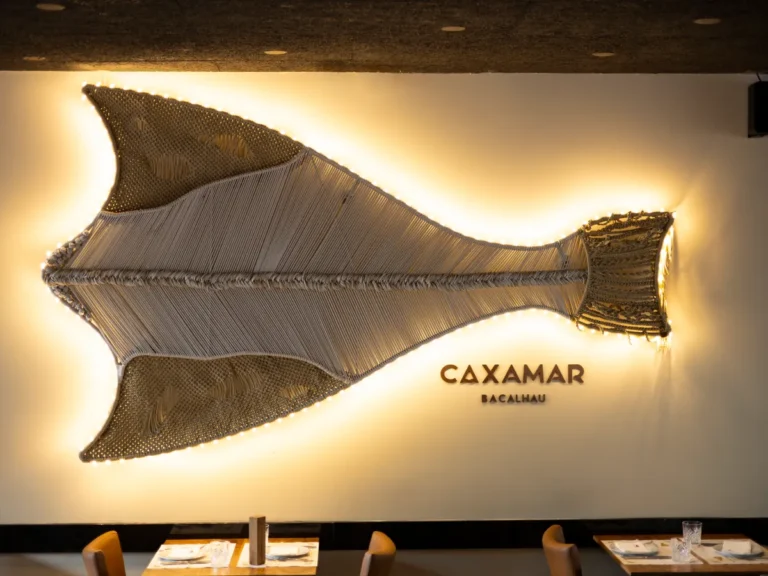Escultura luminosa de bacalhau na parede do restaurante