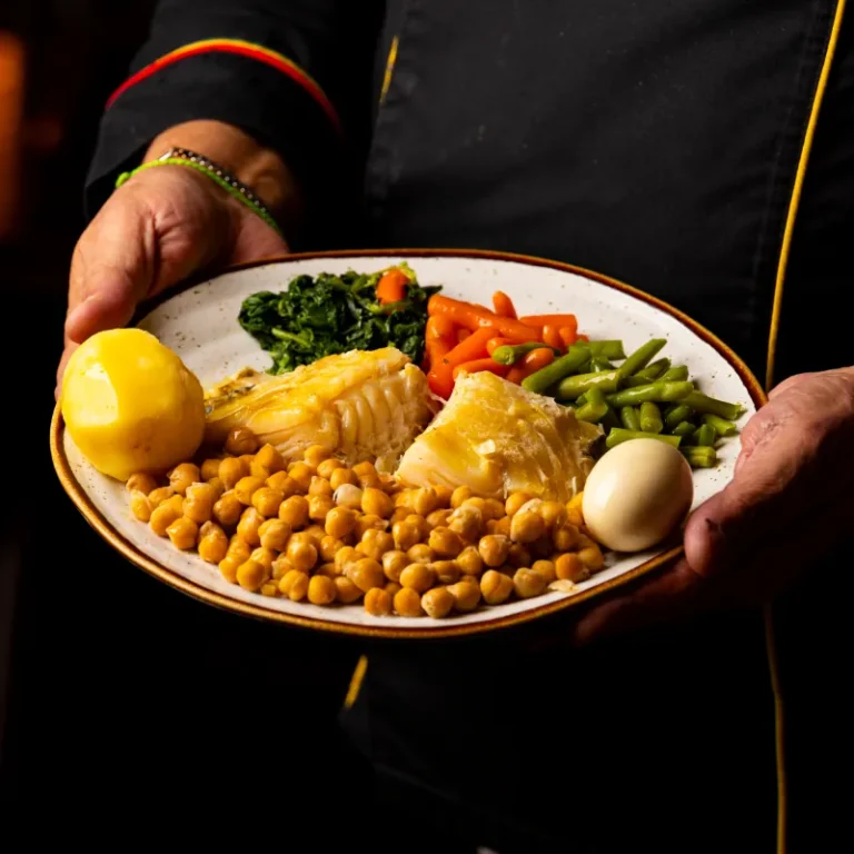 Bacalhau cozido com grão, legumes e ovo, servido pelo chef
